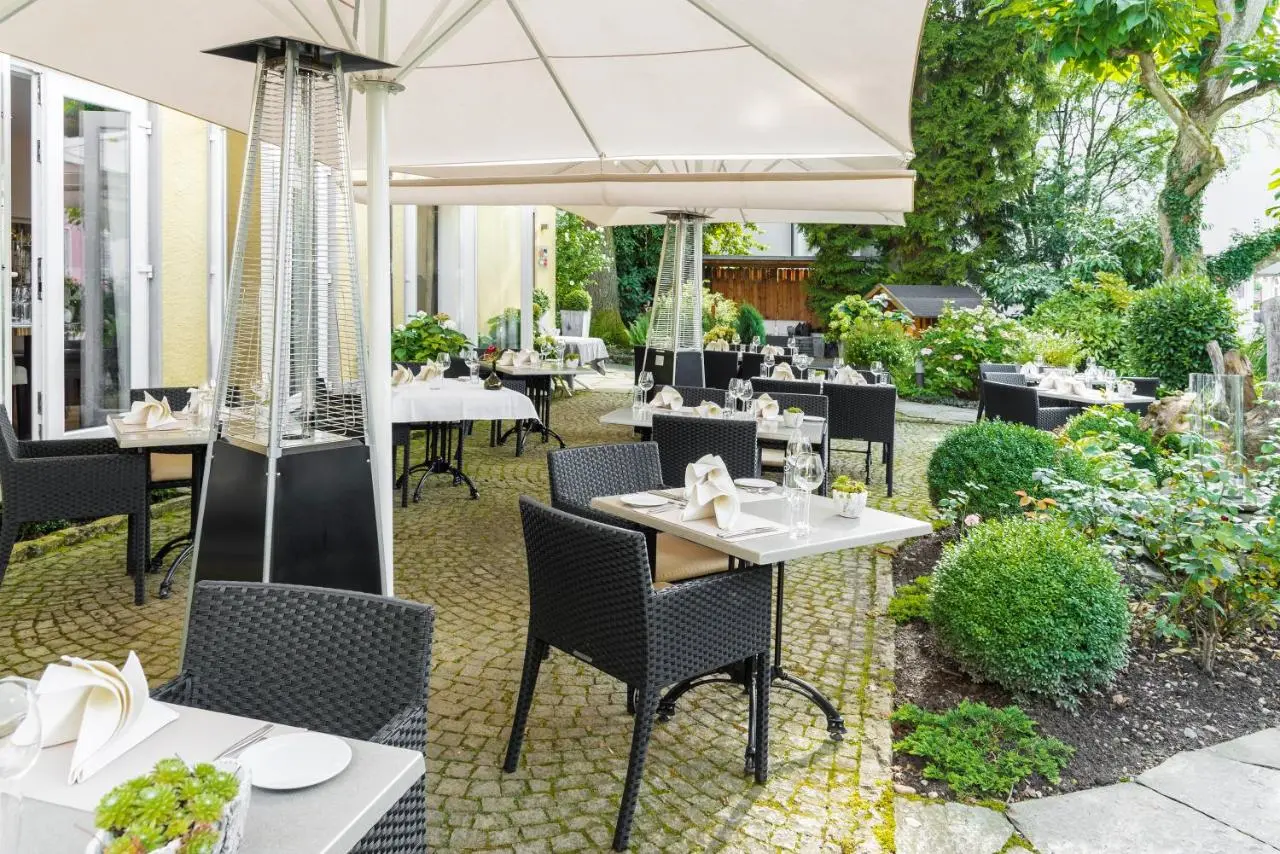 Gedeckte Tische unter Schirmen im grünen Garten der Villa Friesinger